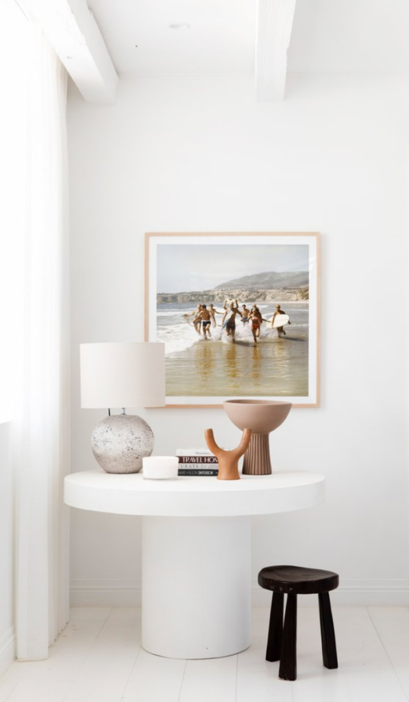 white entry table with styling objects and artwork above
