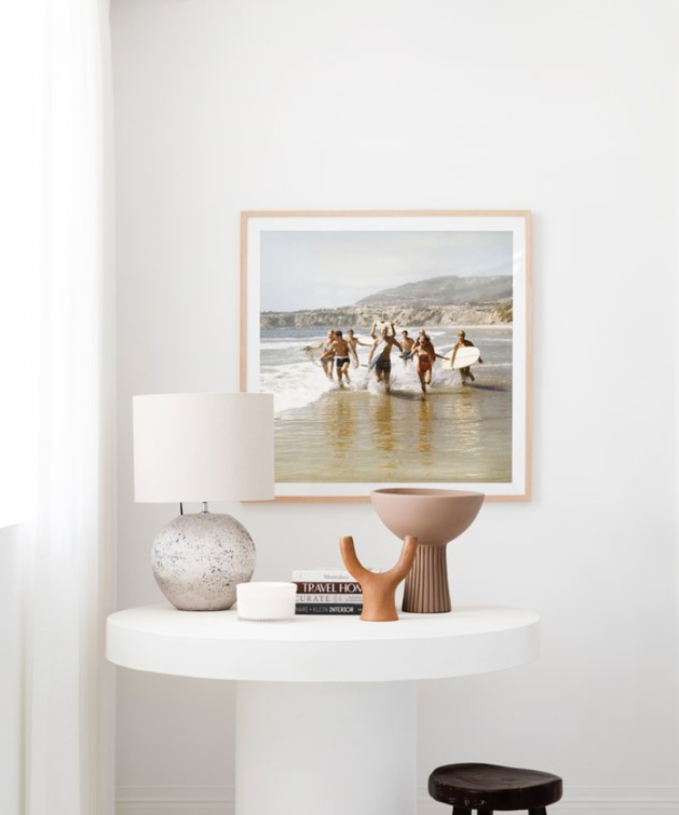 white entry table with styling objects and artwork above